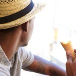 Man wearing a sunhat and eating an ice cream cone